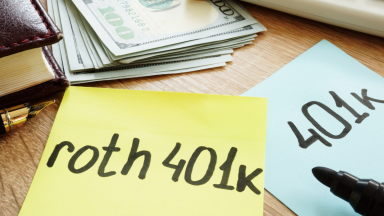 table with misc office supplies, including two post-it notes, one reading roth 401k, the other with 401k. a stack of money, opened marker, and closed book can also be seen