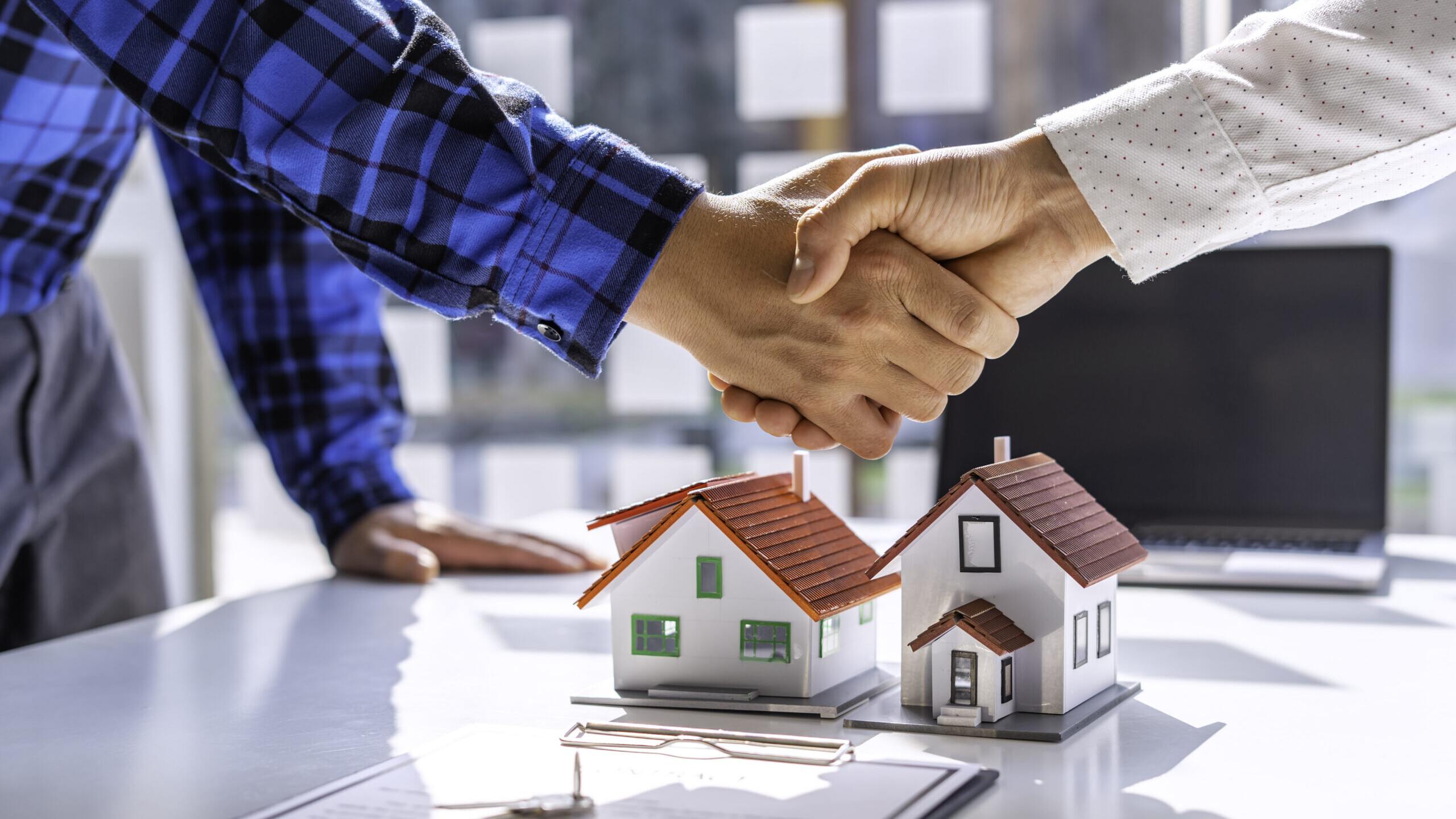 Real estate agents and clients shake hands and deliver the keys.