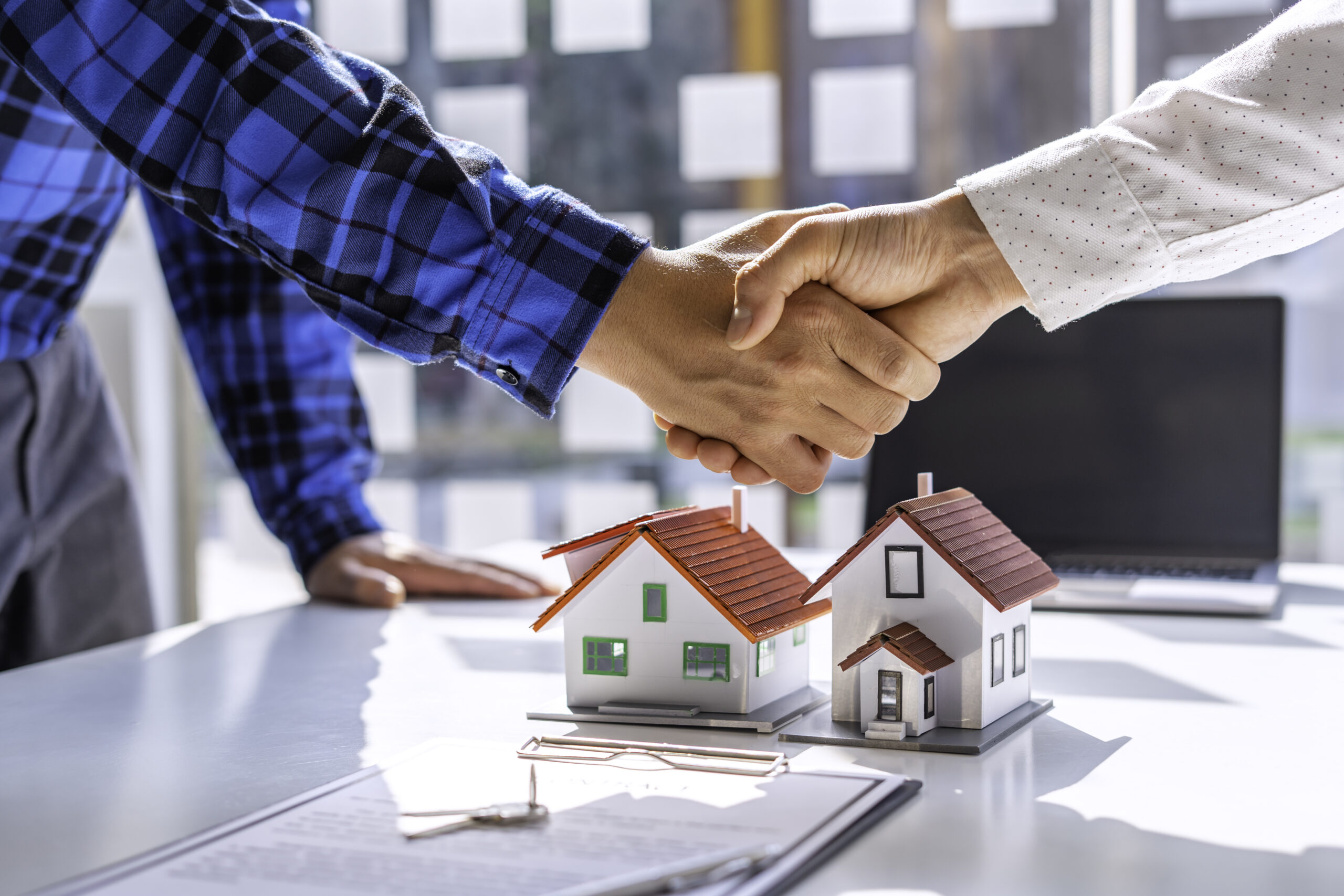 Real estate agents and clients shake hands and deliver the keys.
