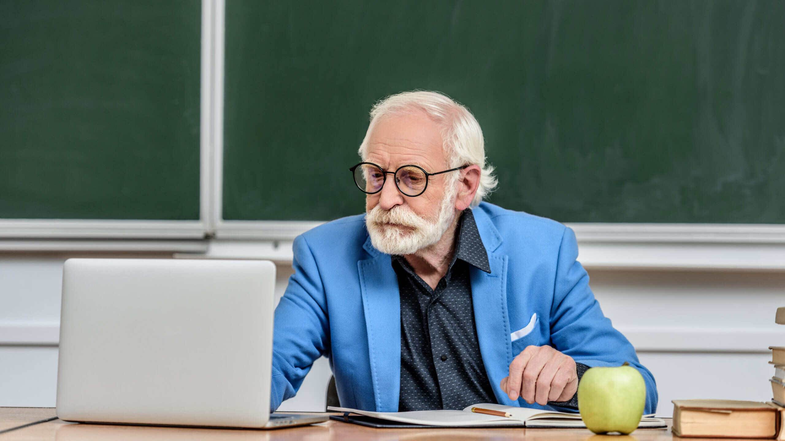 Veteran teacher at his classroom desk reviewing whether his 457(b) can be converted to a Roth