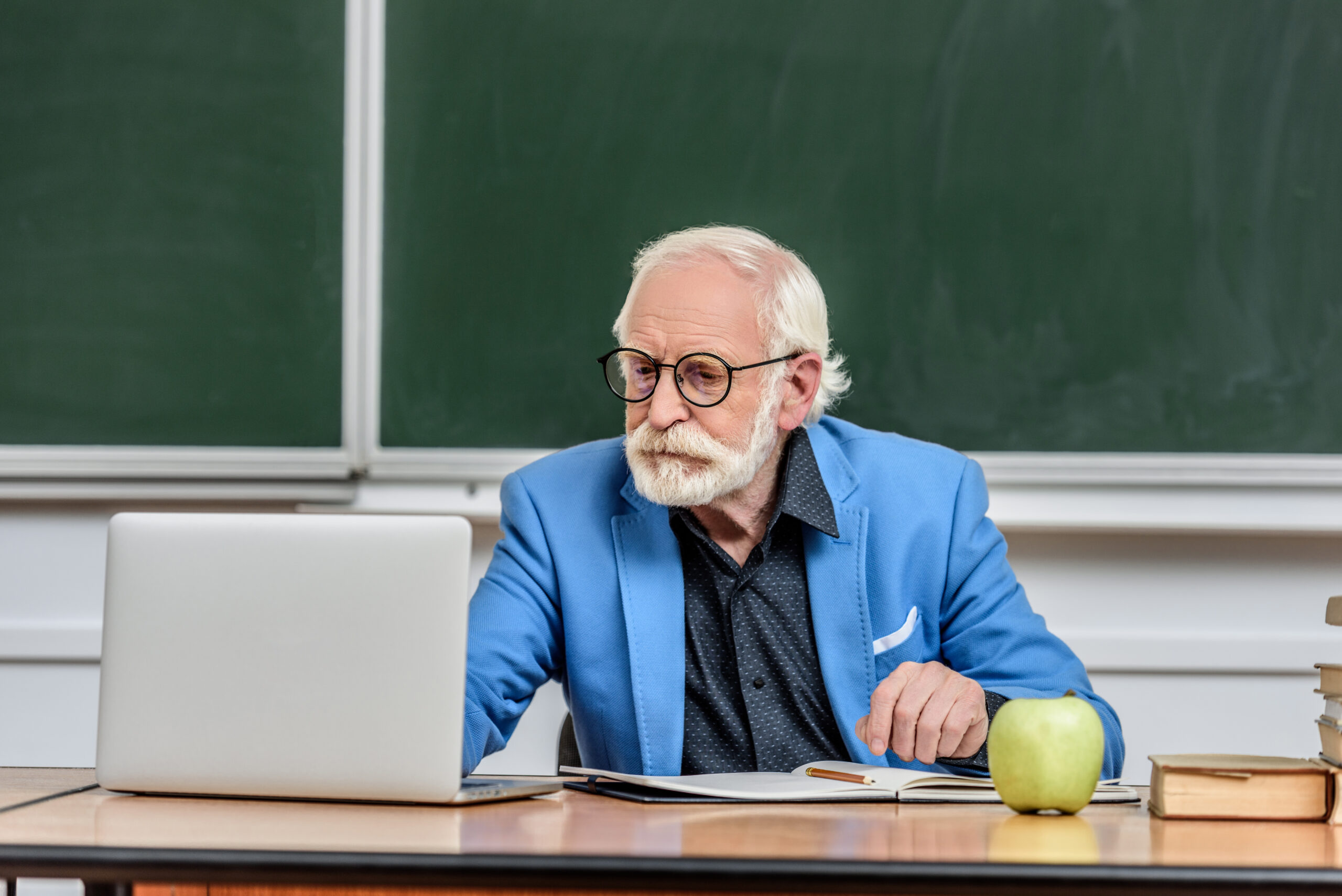 Veteran teacher at his classroom desk reviewing whether his 457(b) can be converted to a Roth